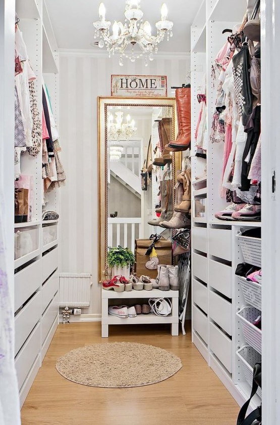a small vintage inspired sweet closet with a large mirror, a crystal chandelier, open shelves and holders plus drawers
