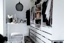 32 a small white closet with holders, shelves and lots of drawers, with a tiny table for makeup and a black pendant lamp