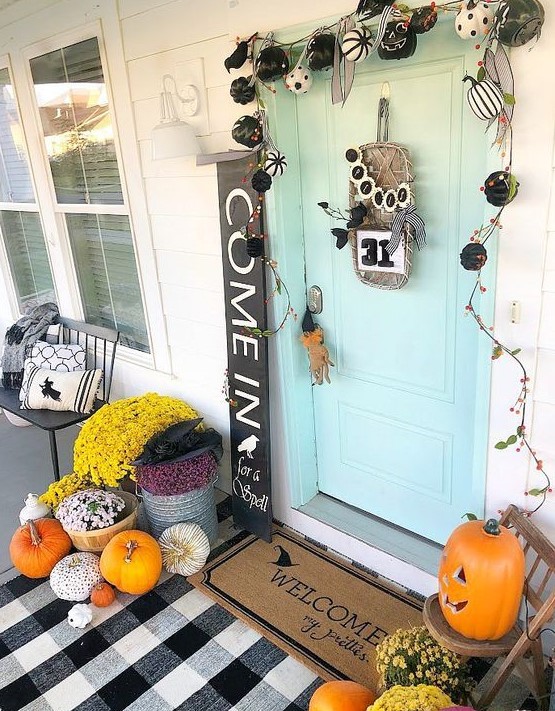 a mini black and white pumpkin garland, bright fall blooms in baskets, bright pumpkins, a sign and a plaid mat