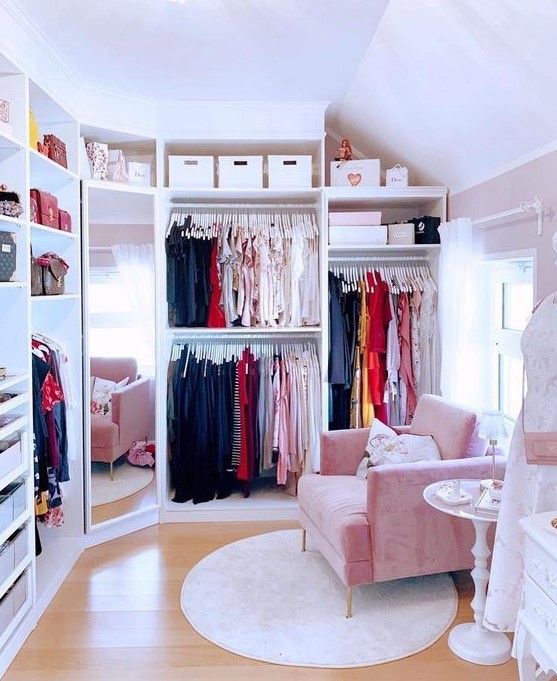 a tiny cute closet with lots of clothes on hangers, some drawers for small stuff and accessories and shelves for bags plus a pink chair