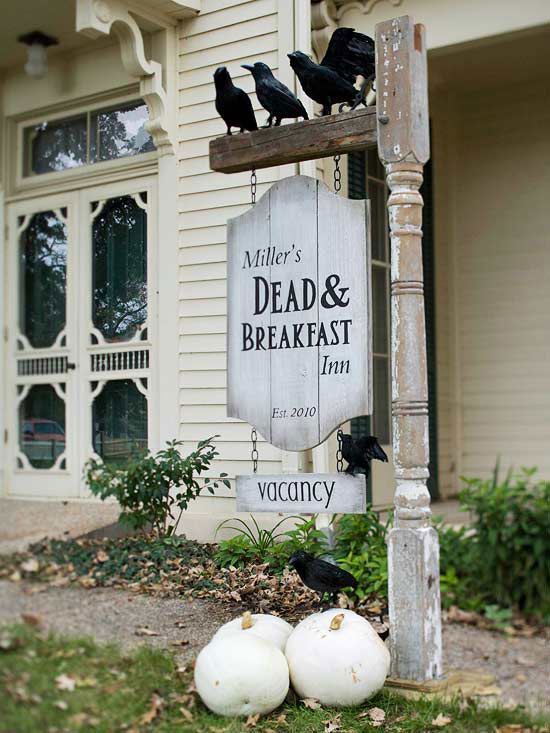 a vintage farmhouse Halloween sign with faux blackbirds, a sign hanging on chain and some pumpkins under it are great for outdoors