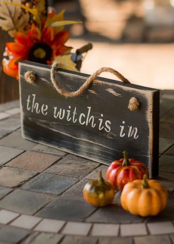 a wooden sign paired with some faux pumpkins for chic and stylish Halloween decor