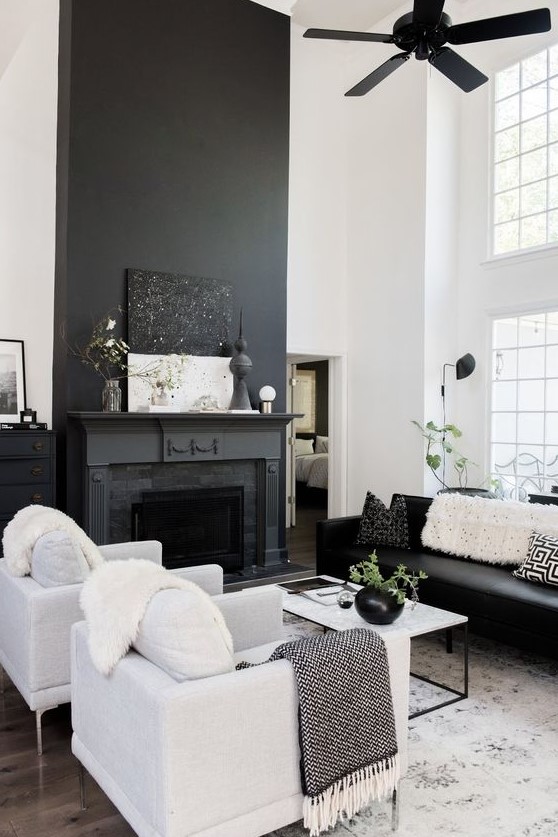 a Nordic living room with a black fireplace, black and white furniture, a black fan and a white coffee table
