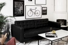 a Nordic living room with a gallery wall, a white stove, a printed rug and a black leather sofa plus greenery