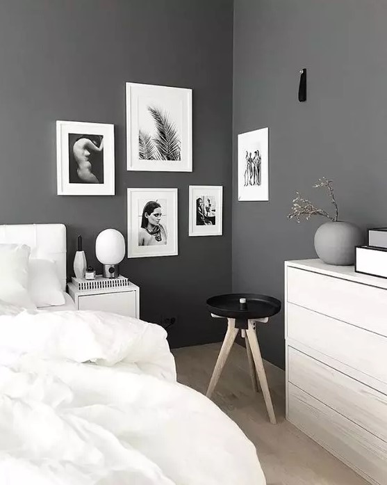 a Scandinavian bedroom with grey walls, white furniture, white bedding, a catchy black and white gallery wall in the corner