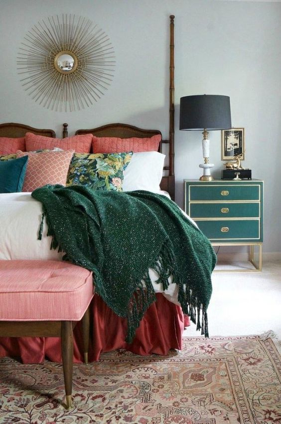 a beautiful eclectic bedroom with grey walls, a dark-stained bed with colorful bedding, a pink upholstered bench, teal nightstands
