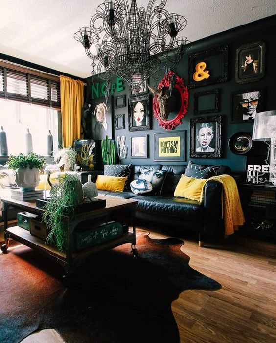 a beautiful eclectic living room with a black accent wall and a bold gallery wall, a black sofa and bright pillows, a tiered coffee table and a black chandelier