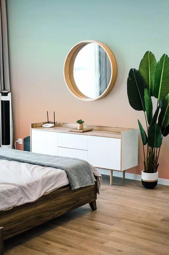 a bedroom with a gradient sunset wall, from mint to coral, a Scandinavian dresser, a dark stained bed with neutral bedding
