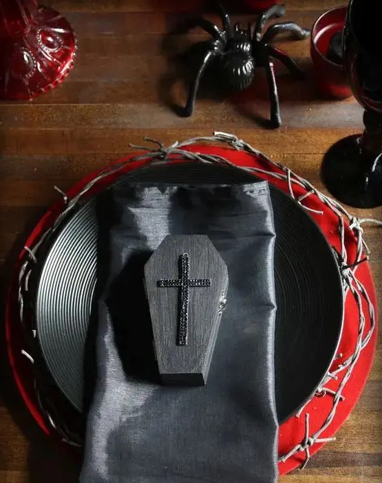 a black and red tablescape with spiders, coffins and textured chargers for a vampire party