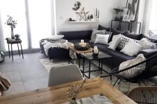 a black and white Scandi living room with a black sectional, a round chair, a black console , a tree slice coffee table and candles