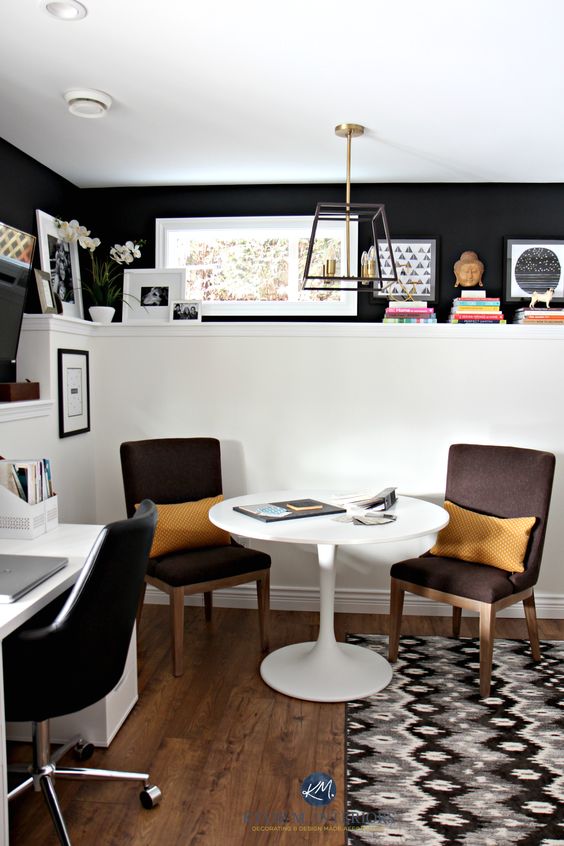 a black and white farmhouse home office with black and white walls, a white desk and a table, black and brown chairs and some decor