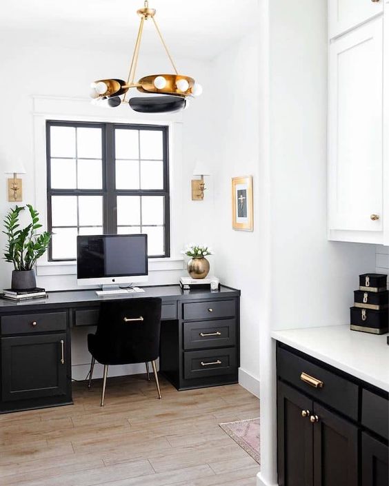 a black and white modern farmhouse home office with a black desk and a chair, a chic brass and black chandelier, potted plants