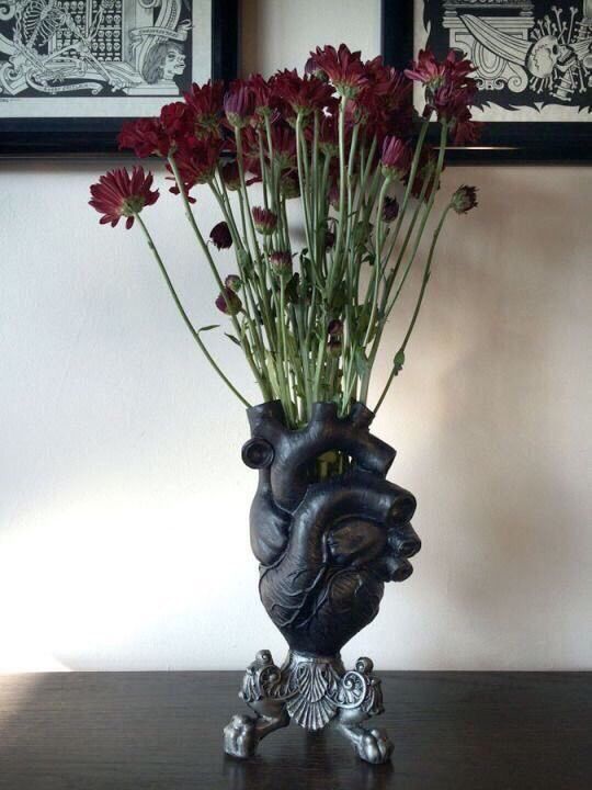 a black heart vase with deep red blooms on a stand is a bold and catchy idea for Halloween decor