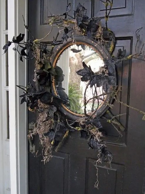 a black mirror with branches, twigs, black leaves and blackbirds is a lovely front door decoration for those who love vintage Halloween decor