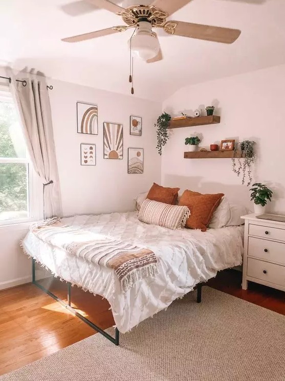 a boho teen bedroom with a metal bed, a gallery wall, wall mounted shelves, a white dresser, potted greenery and neutral textiles