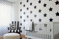 a bold black and white nursery with a geo printed rug, a white crib and printed bedding, a star printed accent wall, printed textiles