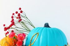 a bold blue pumpkin decorated with gold sequins that form a word is a cool and bright idea for Halloween