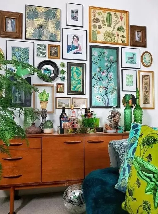 a botanical gallery wall with various art in mismatching frames and even faux succulents right on the wall is wow