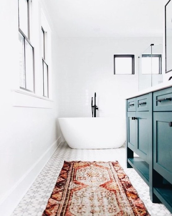 a bright eclectic bathroom done in white and neutrals and accented with a red boho rug and a teal vanity