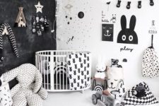 a catchy and bold nursery with a black wall, some prints, a gallery wall of artworks and garlands and lot sof toys