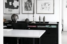 a catchy and stylish black and white home office with a black storage unit, a black and white desk, a black chair and a mini gallery wall of three pieces