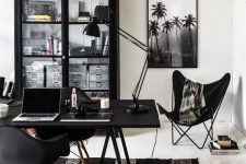a catchy boho black and white home office with a black storage unit, a black desk and chairs, black lamps and a boho printed rug plus greenery