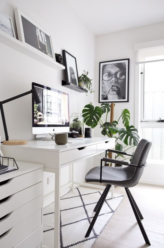 a chic Nordic home office with a white desk and a cabinet, a grey chair, shelves with artworks and some potted plants