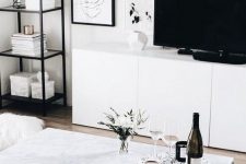 a chic Nordic living room with white furniture, some touches of black and a gallery wall, prints are incorporated with a rug