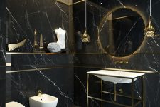 a chic contemporary black and gold bathroom with a lit up round mirror, white appliances, pendant lamps and black marble tiles all over