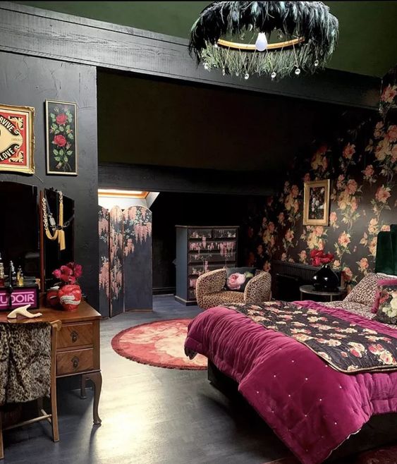 a chic eclectic bedroom with black walls and a black floral one, a bed with purple and floral bedding, a vintage vanity, a feather chandelier and some art