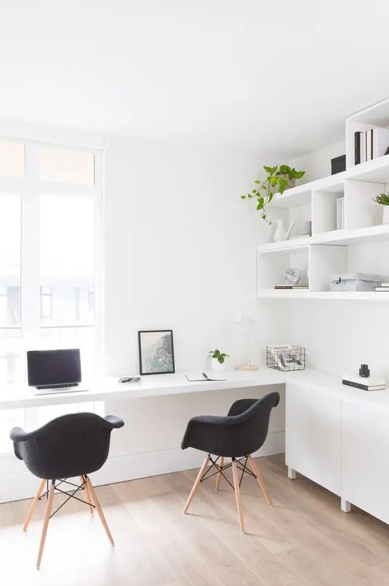 a chic minimalist home office with a wall-mounted shelving unit, a storage one and a floating desk plus black chairs