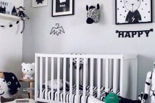 a classy Scandinavian nursery with a gallery wall, pillows, a white crib and shelves for storage