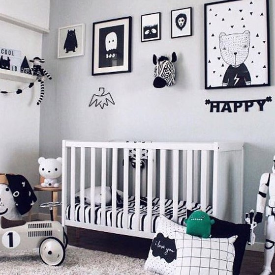 a classy Scandinavian nursery with a gallery wall, pillows, a white crib and shelves for storage