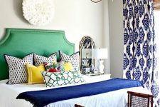 a colorful eclectic bedroom in bold blue and emerald green, with a mix of prints and vintage touches