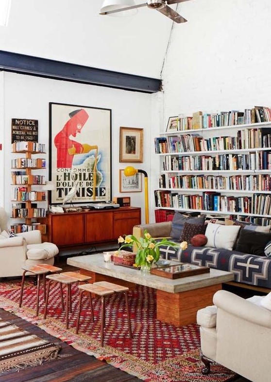 a colorful eclectic living room with open bookshelves, bright printed textiles, neutral furniture and touches of mid-century modern