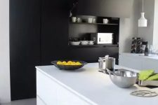 a contemporary black and white kitchen with a built-in matte storage unit, sleek white cabinets and a kitchen island, pendant lamps and a lot of natural light