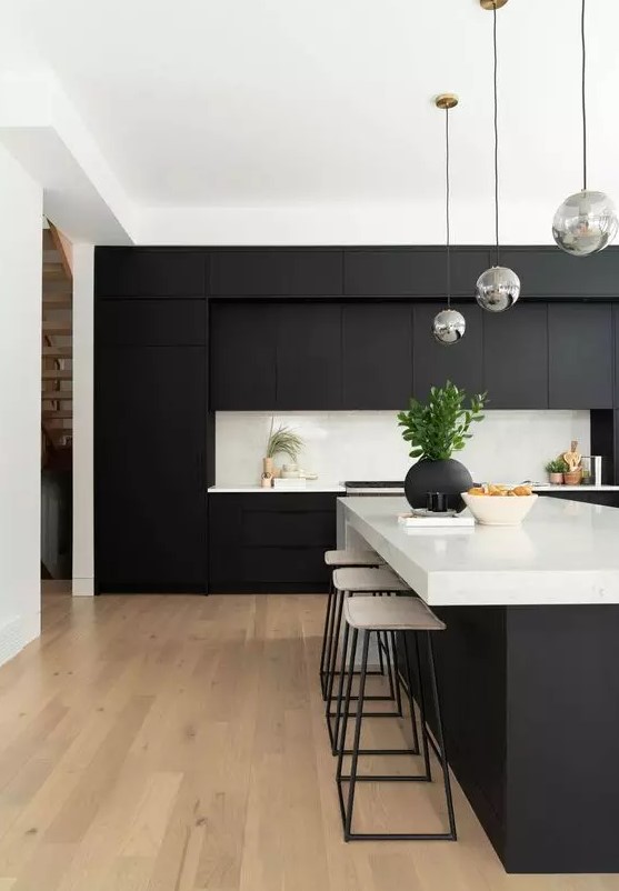 a contemporary black and white kitchen with matte cabinets, white countertops and a backsplash and bubble lamps