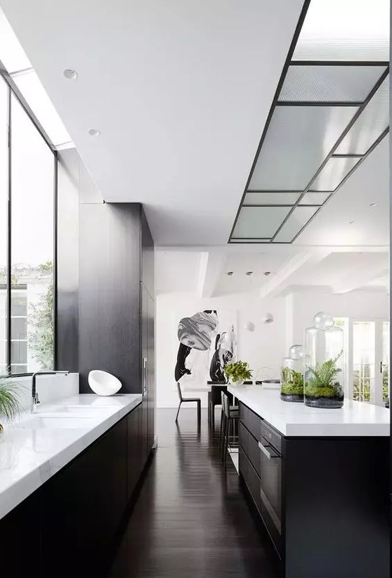 a contemporary black and white kitchen with white countertops, a window as a backsplash and built-in lights