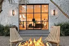 a contemporary outdoor space done with gravel, a couple of wooden chairs and a concrete fire bowl is amazing