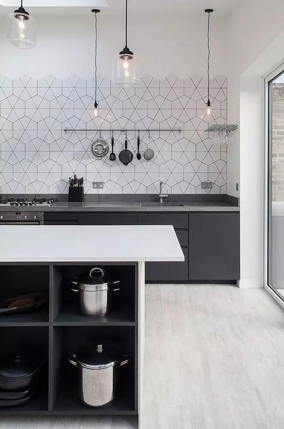 a contrasting Scandinavian kitchen in black, grey and white, black cabinets with grey countertops, a white kitchen island and hex tiles