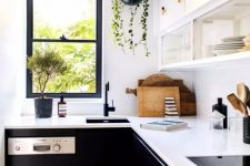 a contrasting kitchen with white upper and black lower cabinets, white countertops and black fixtures plus greenery in pots
