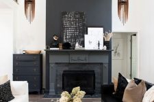 a contrasting living room with a black fireplace and a styled mantel, a black dresser, a black and white sofa, a coffee table and wooden pendant lamps