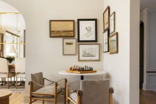 a cool chess nook with a round table and grey chairs, a chic vintage corner gallery wall with black and metallic frames