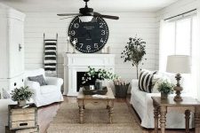 a cozy farmhouse living room in black and white is warmed up with natural wooden furniture and potted greenery