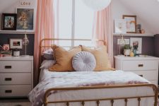 a cozy modern teen bedroom with a brass bed with bedding, white nightstands, lamps and some art plus a printed rug
