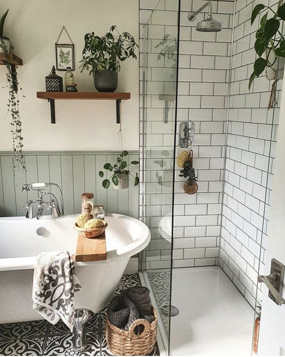 a cute Scandinavian bathroom with white subway tiles, grey paneling, a black and white tile floor, a clawfoot tub and potted greenery