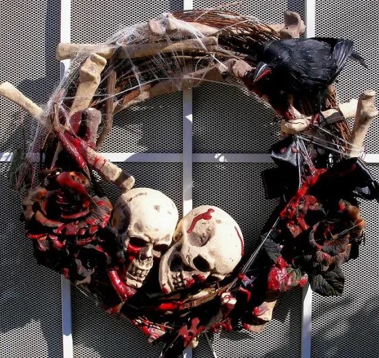 a dark Halloween wreath with black bloody roses, bones, skulls and spiderwebs is a cool idea for frightening your visitors