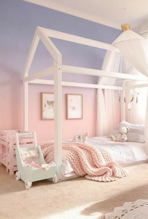 a dreamy kid's room with a house-shaped bed with pastel bedding, a gradient lilac to pink accent wall and some pastel textiles and toys