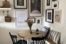 a farmhouse dining nook with a round table, black chairs and a bench and a cool contrasting corner gallery wall is lovely