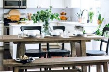 a fresh contemporary kitchen in white with a rustic dining zone with benches and touches of blakc for drama
